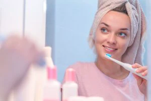 Happy attractive healthy woman brush teeth using ultrasonic elec
